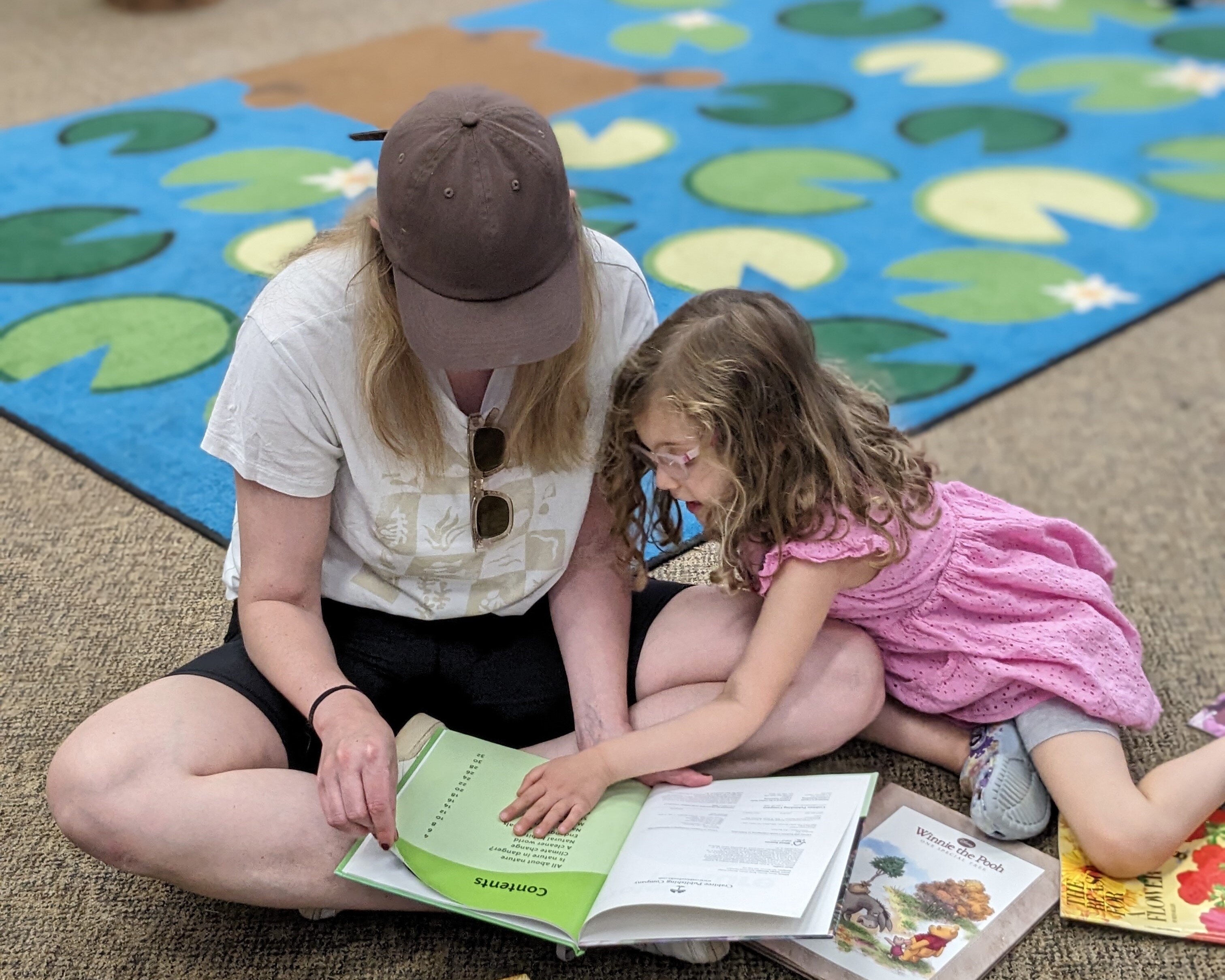 child and adult turning pages of a book